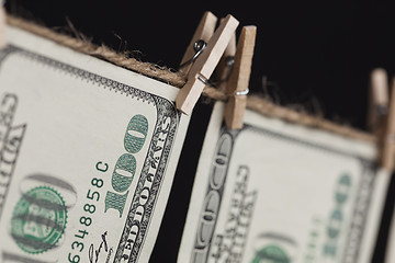 Image showing Hundred Dollar Bills Hanging From Clothesline on Dark Background