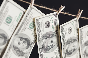 Image showing Hundred Dollar Bills Hanging From Clothesline on Dark Background