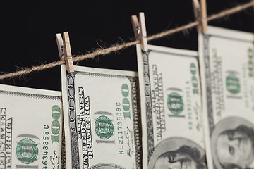 Image showing Hundred Dollar Bills Hanging From Clothesline on Dark Background