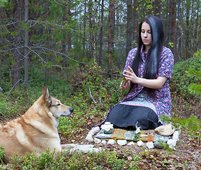 Image showing Girl witch conjures in the woods. Near a huge dog 