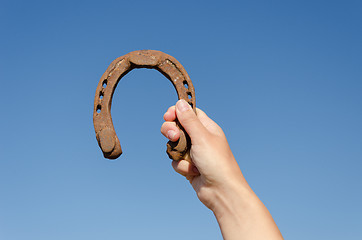 Image showing hand hold vintage horseshoe on blue sky background 