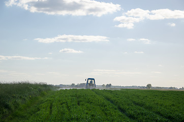 Image showing Tractor spray field with chemicals and worker man 