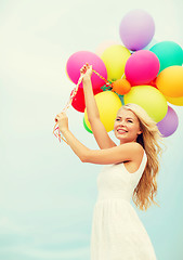 Image showing smiling woman with colorful balloons outside