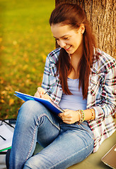 Image showing smiling teenager writing in notebook