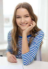 Image showing smiling teenage girl with notebook at home