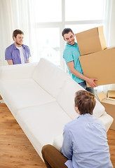 Image showing smiling friends with sofa and boxes at new home