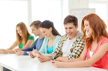 Image showing smiling students with smartphones at school