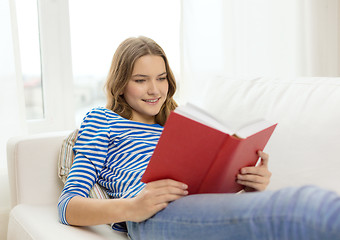 Image showing smiling teenage girl reading book on couch