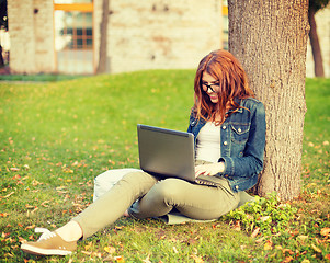 Image showing smiling teenager in eyeglasses with laptop