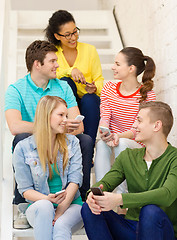 Image showing smiling students with smartphone having discussion