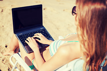 Image showing girl looking at laptop on the beach