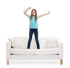 Image showing smiling little girl jumping or dancing on sofa