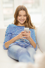 Image showing smiling teenage girl with smartphone at home