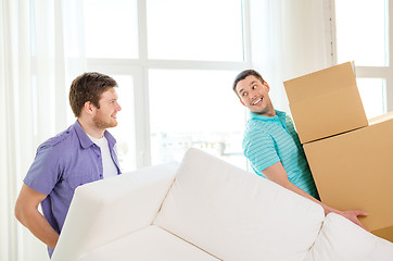 Image showing smiling friends with sofa and boxes at new home