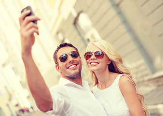 Image showing smiling couple with smartphone in the city