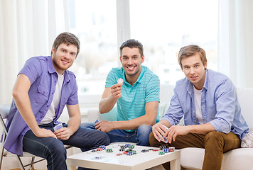 Image showing happy three male friends playing poker at home