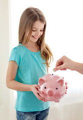 Image showing smiling little girl holding piggy bank