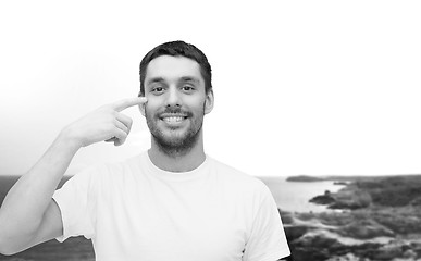 Image showing smiling young handsome man pointing to eyes