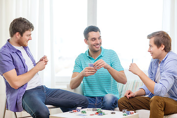 Image showing happy three male friends playing poker at home