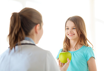 Image showing female doctor giving apple to smiling little girl