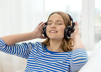 Image showing smiling young girl in headphones at home