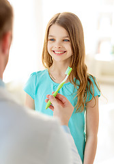 Image showing male doctor giving toothbrush to smiling girl