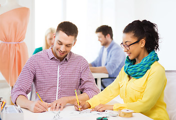 Image showing smiling designers drawing sketches in office