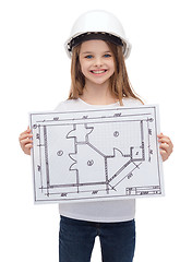 Image showing smiling little girl in helmet showing blueprint