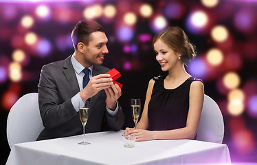 Image showing excited young woman looking at boyfriend with box