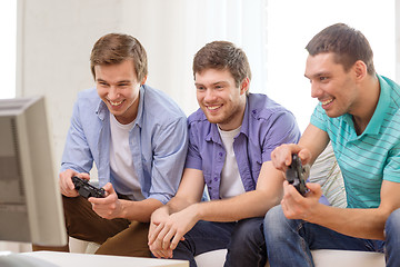 Image showing smiling friends playing video games at home