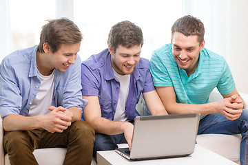 Image showing smiling friends with laptop computer at home