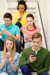 Image showing busy students with smartphones sitting on stairs