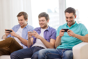 Image showing smiling friends with smartphones at home