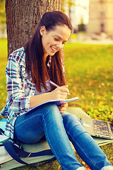 Image showing smiling teenager writing in notebook