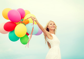 Image showing smiling woman with colorful balloons outside