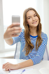 Image showing smiling student girl with smartphone and books