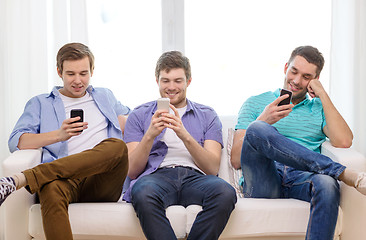 Image showing smiling friends with smartphones at home