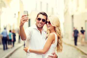 Image showing smiling couple with smartphone in the city