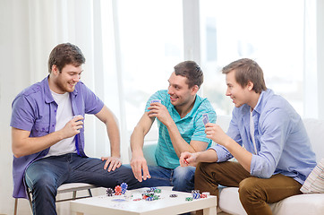 Image showing happy three male friends playing poker at home