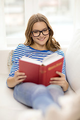 Image showing smiling teenage girl reading book on couch