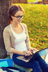 Image showing smiling teenager in eyeglasses with laptop