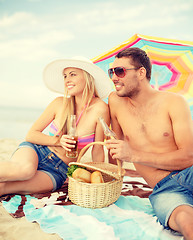 Image showing smiling couple having picnic on the beach