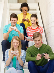 Image showing smiling students with smartphone texting at school