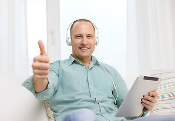 Image showing smiling man with tablet pc and headphones at home