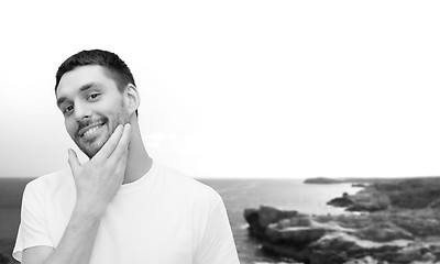 Image showing beautiful smiling man touching his face