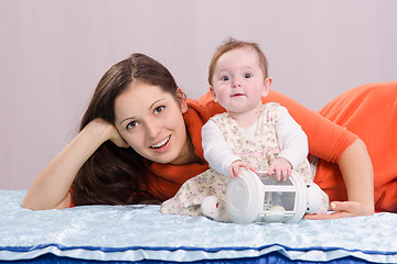 Image showing Mom with a six-month daughter playing on the bed