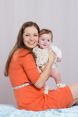 Image showing Mom with a six-month daughter sitting on bed