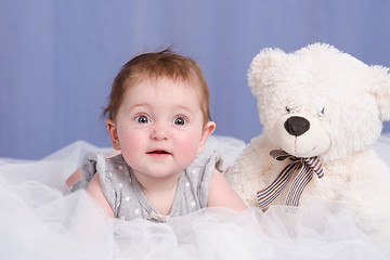 Image showing Six-month baby girl with teddy bear lying on couch