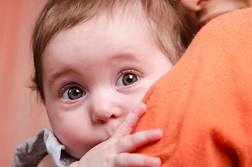 Image showing Scared kid hiding behind mom's shoulder