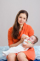 Image showing Mum feeds from a bottle daughter